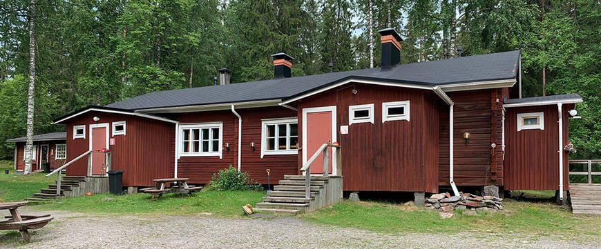 Rajalan leirikeskuksen punamultaiset majoitustilarakennukset kesäisessä ympäristössä.